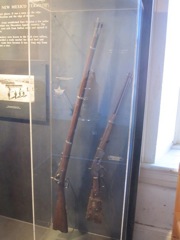 Weapons display of a 1865 (First Allin Conversion) or 1866 (Second Allin Conversion) Springfield Rifle .58-60-500 rimfire (if its an 1865) or .50-70-450 if its a 1866.

Winchester 1873 (unknown caliber)